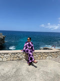 The Indigo Tide Caftan in deep violet tie-dye, worn oceanside
